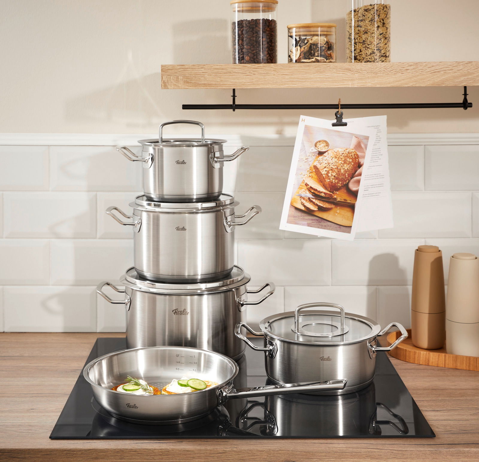 Topfset Original-Profi 5-tlg. aus Edelstahl, bestehend aus mehreren Töpfen und einer Pfanne, auf einem modernen Herd in einer stilvollen Küche, seitliche Perspektive.