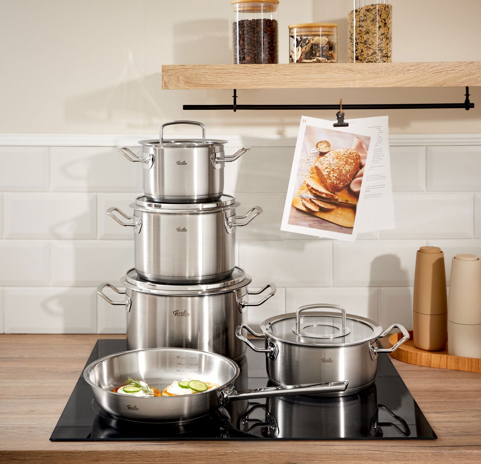 Topfset Original-Profi 5-tlg. aus Edelstahl, bestehend aus mehreren Töpfen und einer Pfanne, auf einem modernen Herd in einer stilvollen Küche, seitliche Perspektive.