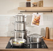 Topfset Original-Profi 5-tlg. aus Edelstahl, bestehend aus mehreren Töpfen und einer Pfanne, auf einem modernen Herd in einer stilvollen Küche, seitliche Perspektive.