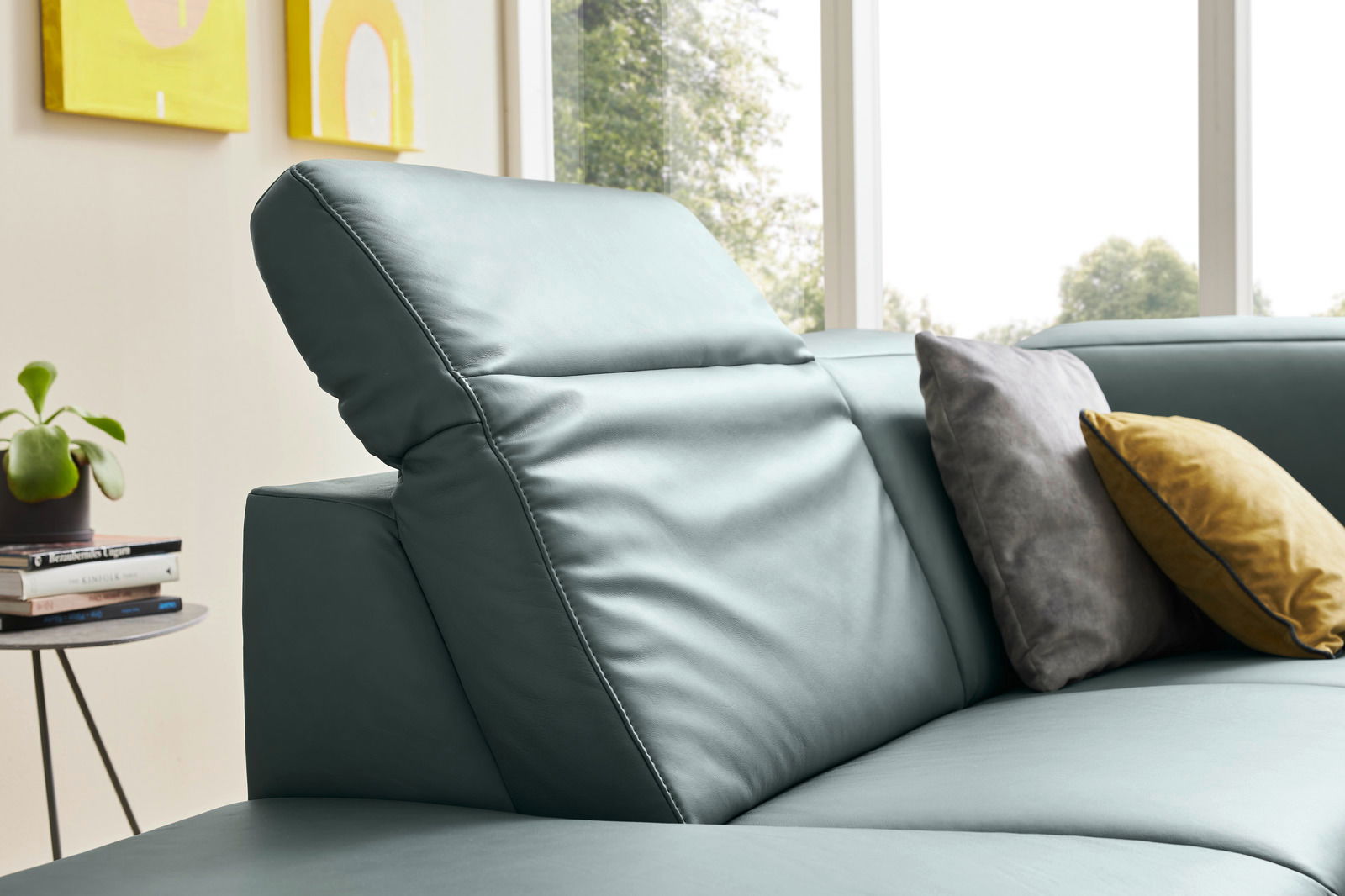 Nahaufnahme einer modernen Eckgarnitur mit verstellbarer Rückenlehne in einem hellen Raum, dekoriert mit bunten Kissen. Seitliche Perspektive.