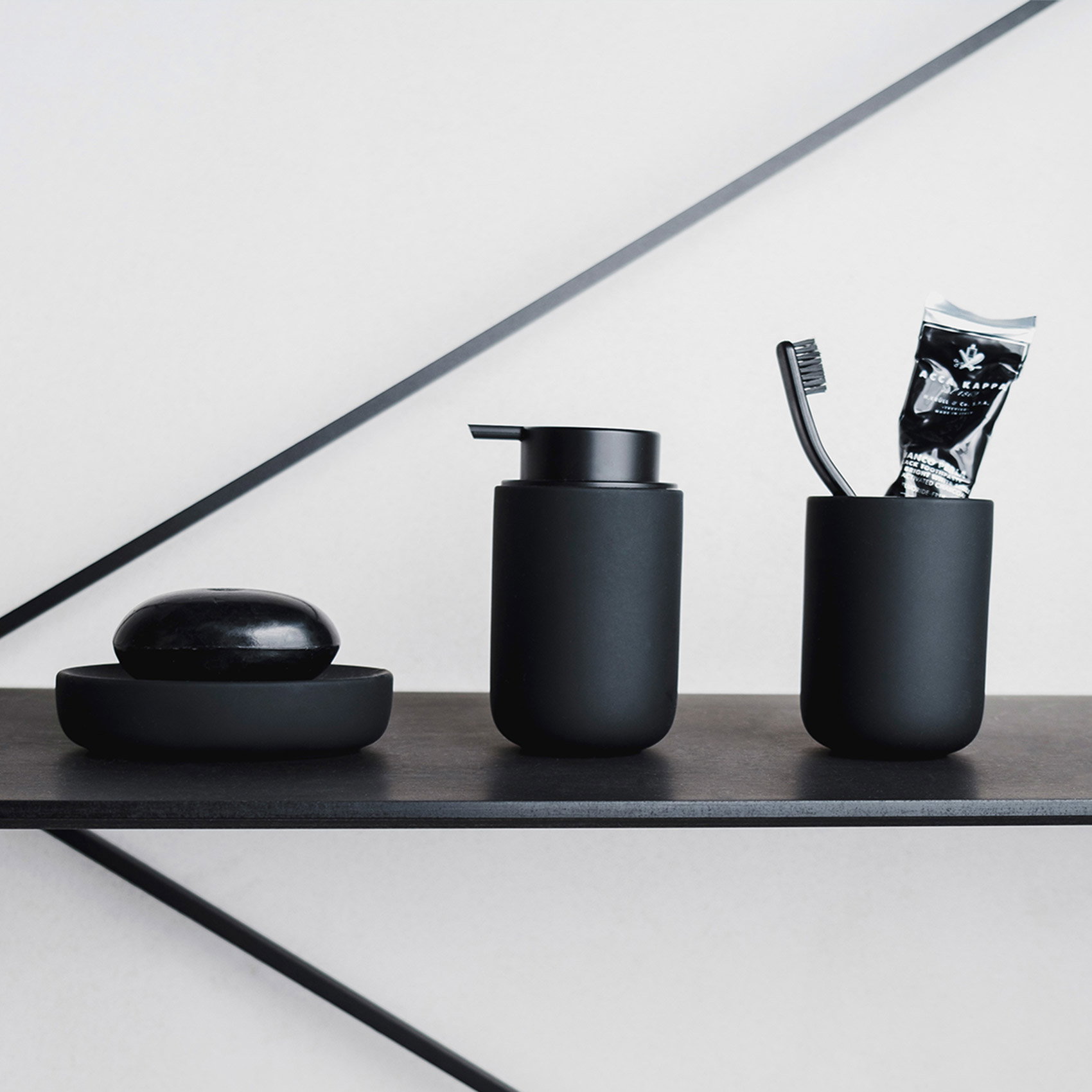 Stilvolle Badezimmeraccessoires in Schwarz: Seifenspender, Zahnputzbecher und Seifenschale auf Ablage