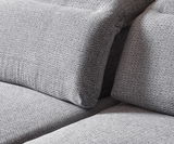 Nahaufnahme einer grauen Longchairkombination mit strukturierter Stoffoberfläche, seitliche Perspektive.