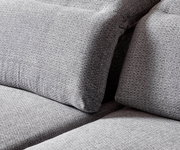 Close-up van een grijze longchair-set met een gestructureerd stoffen oppervlak, gezien vanaf de zijkant.