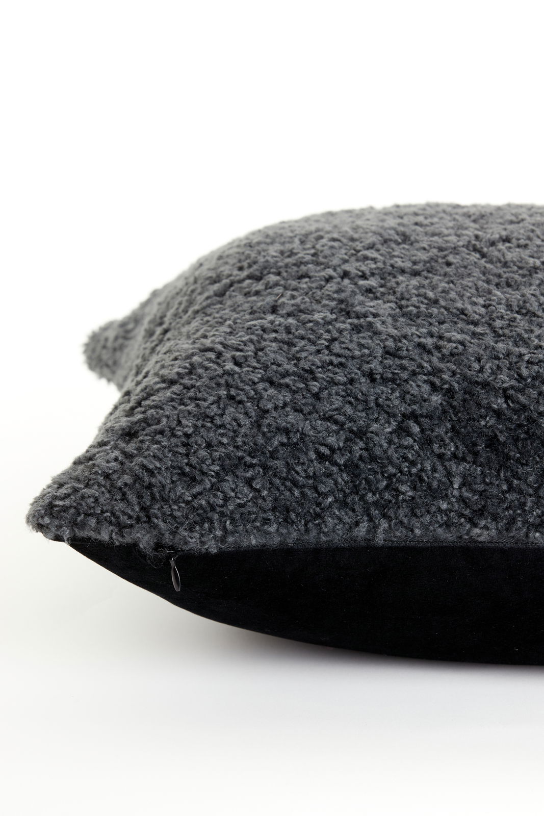 Nahaufnahme eines dunkelgrauen Kissens mit flauschiger Oberfläche, seitliche Perspektive