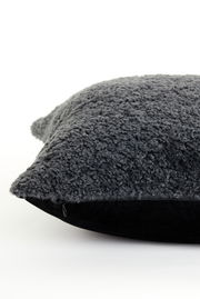 Nahaufnahme eines dunkelgrauen Kissens mit flauschiger Oberfläche, seitliche Perspektive