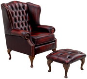 Klassischer Ohrensessel mit rotem Lederbezug und passendem Hocker, seitliche Perspektive
