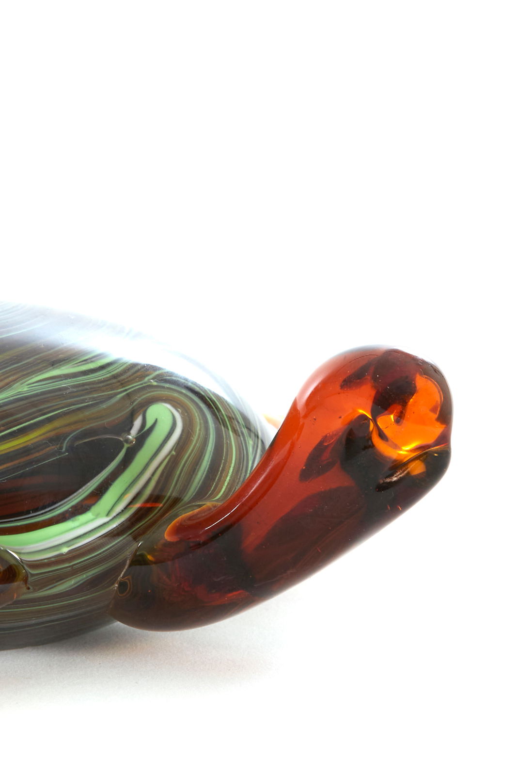 Nahaufnahme eines dekorativen Glasornaments mit geschwungenen, mehrfarbigen Mustern in Grün, Braun und Rot.