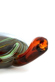 Nahaufnahme eines dekorativen Glasornaments mit geschwungenen, mehrfarbigen Mustern in Grün, Braun und Rot.