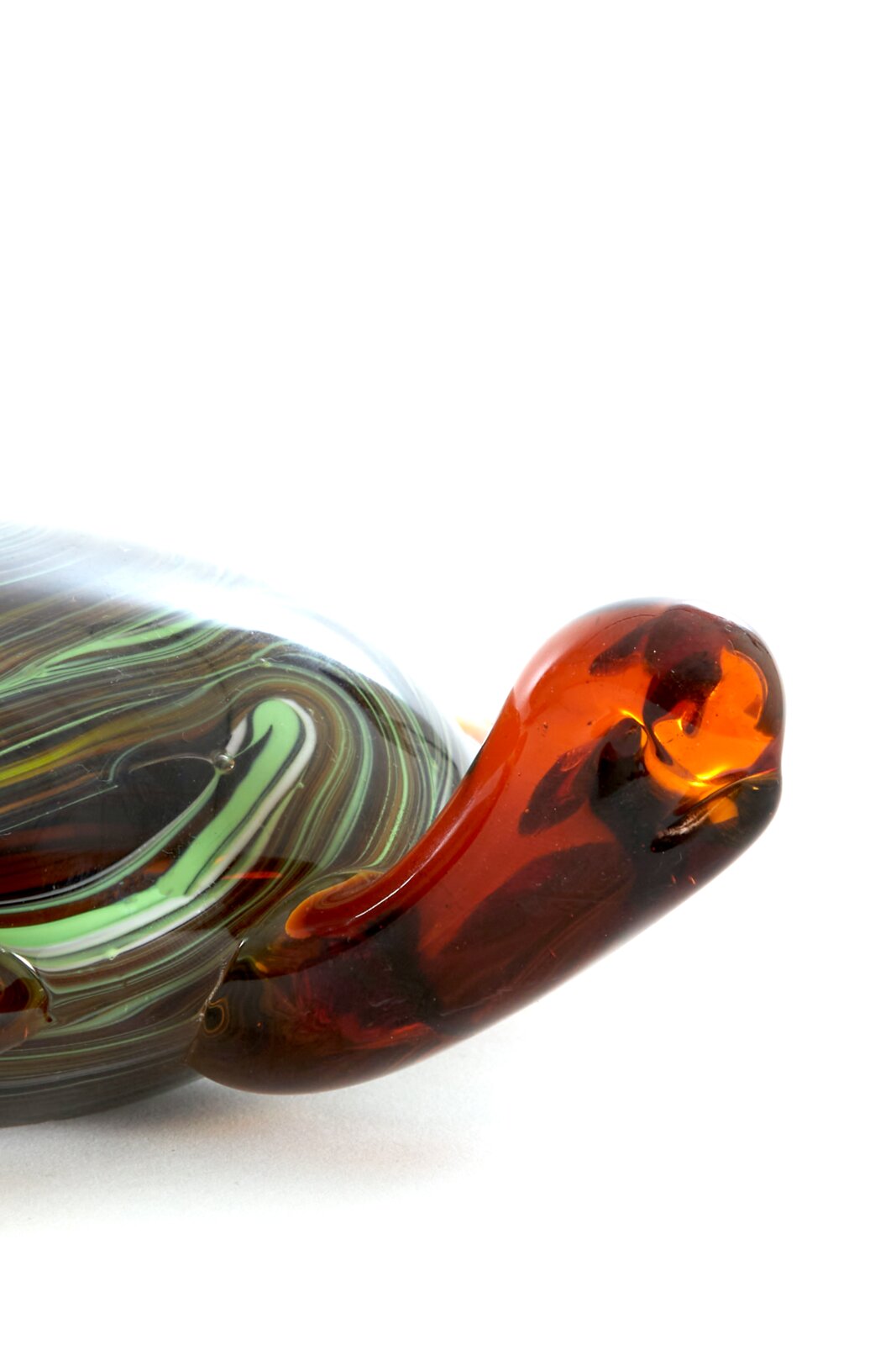 Nahaufnahme eines dekorativen Glasornaments mit geschwungenen, mehrfarbigen Mustern in Grün, Braun und Rot.