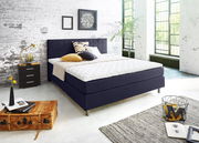 Modernes Boxspringbett in einem stilvollen Schlafzimmer mit industriellem Design, seitliche Perspektive