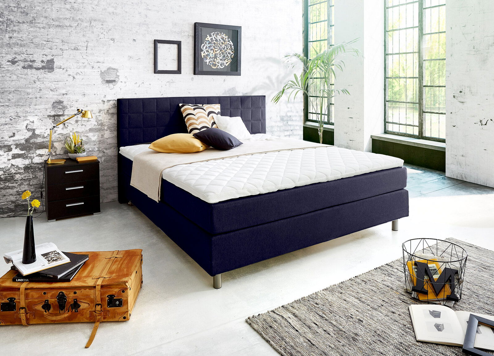 Modernes Boxspringbett in einem stilvollen Schlafzimmer mit industriellem Design, seitliche Perspektive