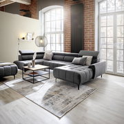 Moderne Polsterrundecke in einem stilvollen Wohnzimmer mit Backsteinwänden und großen Fenstern, seitliche Perspektive