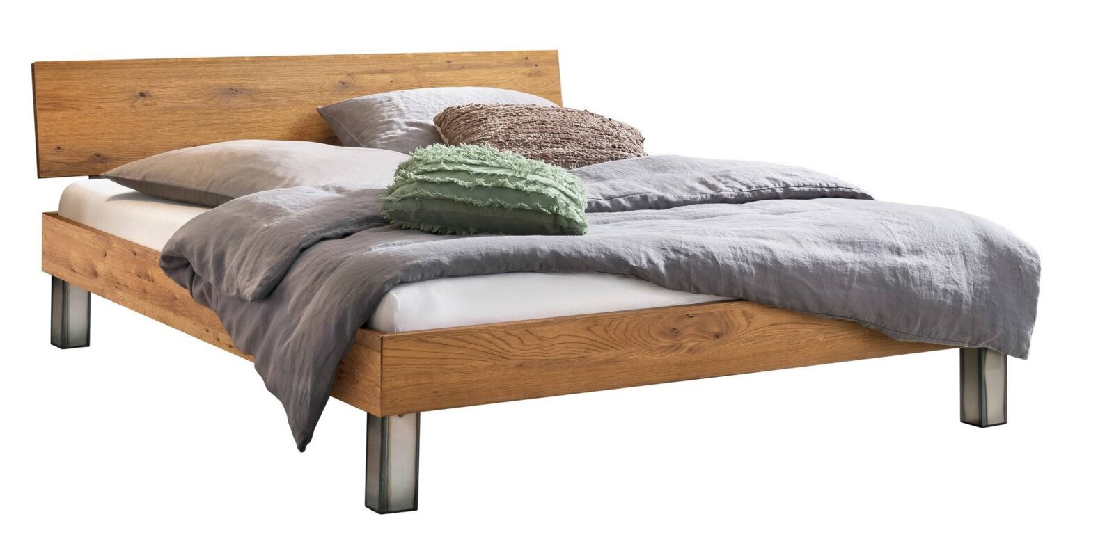 Modernes Holzbett mit breitem Kopfteil und Metallfüßen, bezogen mit grauer Bettwäsche und Zierkissen, in schräger Frontansicht von links (3/4-Perspektive) auf weißem Hintergrund.