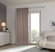 Fertigvorhang in einem modernen Wohnzimmer, aufgehängt an einer Gardinenstange vor einer Glastür, mit Blick auf ein Sofa und eine Kommode.