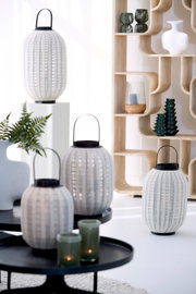 Vooraanzicht van decoratieve witte lantaarns met verticale grijze strepen en zwarte handgrepen in een stijlvol, licht interieur.