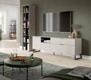 Modernes Wohnzimmer mit wandmontiertem Flachbild-TV über einem hellgrauen Lowboard mit schwarzen Metallfüßen, daneben hohes Regal; Perspektive: frontale Ansicht mit leichtem Blick von links.