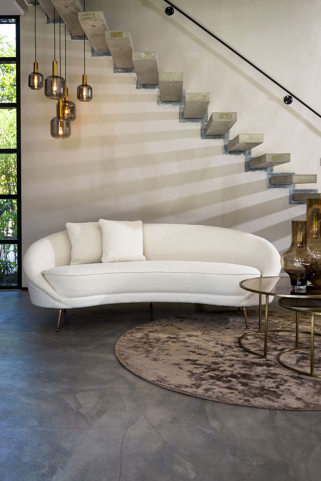 Zwei runde Couchtische aus Glas und Metall in einem modernen Wohnzimmer, fotografiert aus einer seitlichen Perspektive.