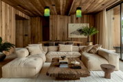 Gemütliches Wohnzimmer mit beiger Couch, rustikalem Holztisch und grünen Hängelampen, Perspektive von vorne.