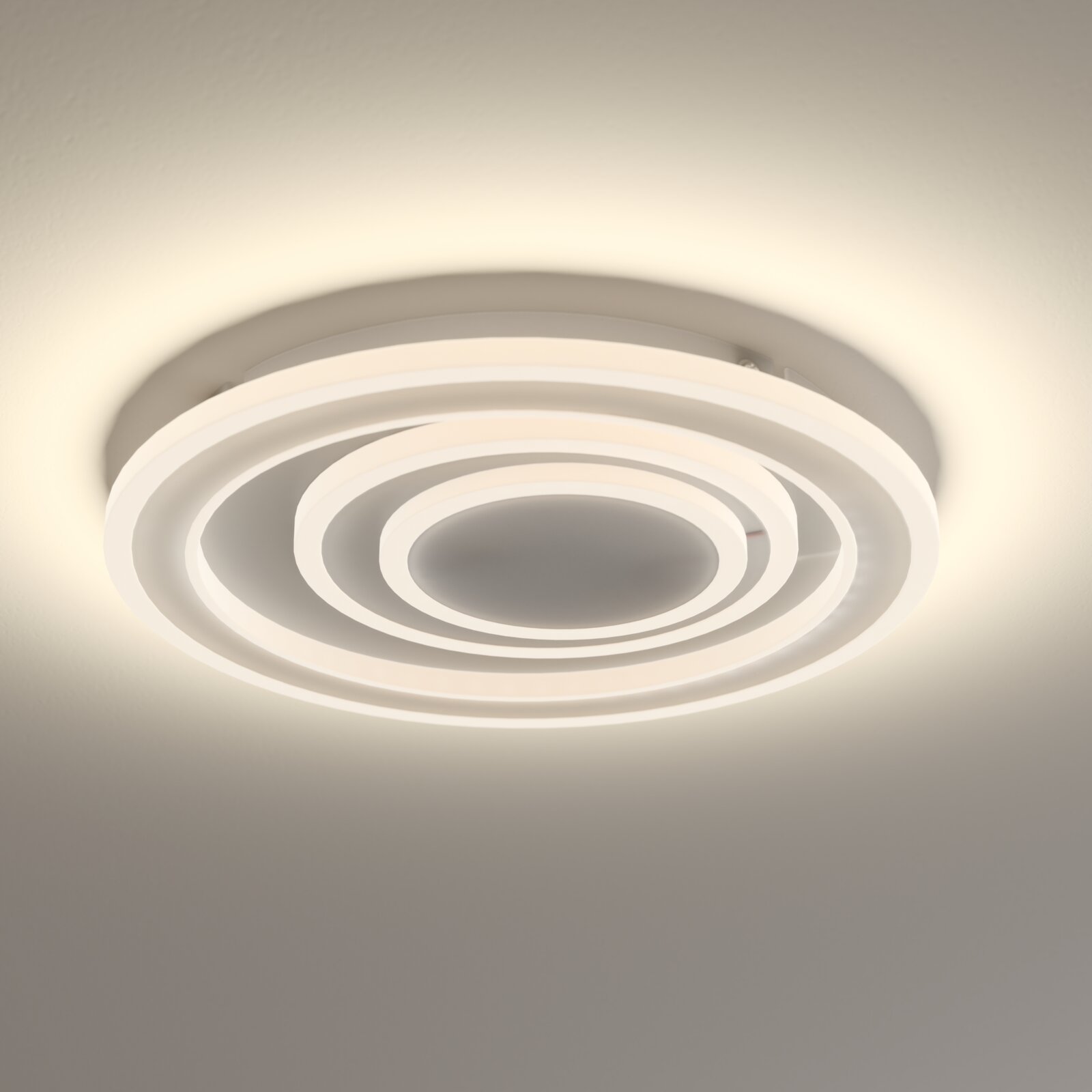 Novel LED-Deckenleuchte DECKENLEUCHTE Moderne runde LED-Deckenleuchte in Weiß mit konzentrischen Leuchtringen, warmweiß leuchtend, fotografiert aus leichter Untersicht (Blick nach oben) an der Decke.