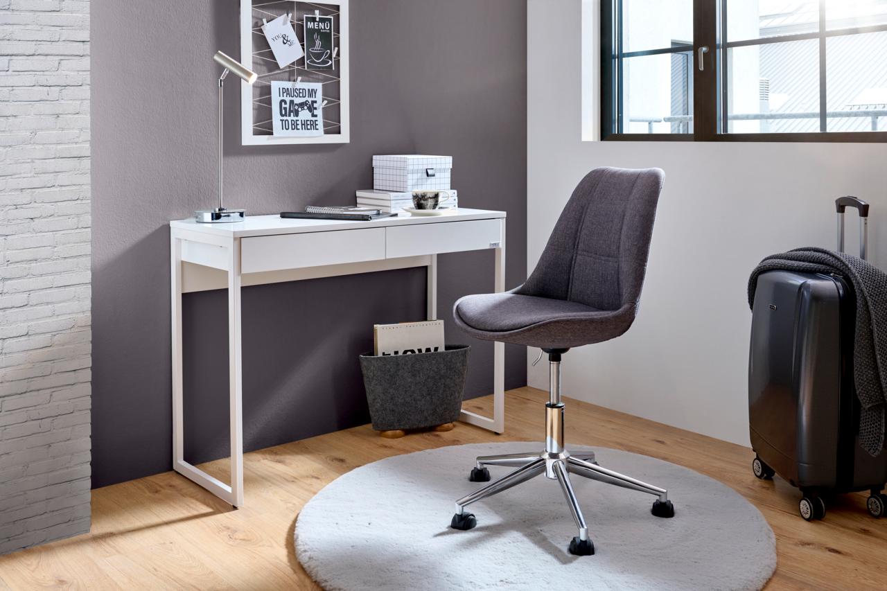 Moderner Schreibtisch in Weiß mit schlankem Design, seitliche Perspektive, ergänzt durch einen grauen Bürostuhl auf einem runden Teppich.