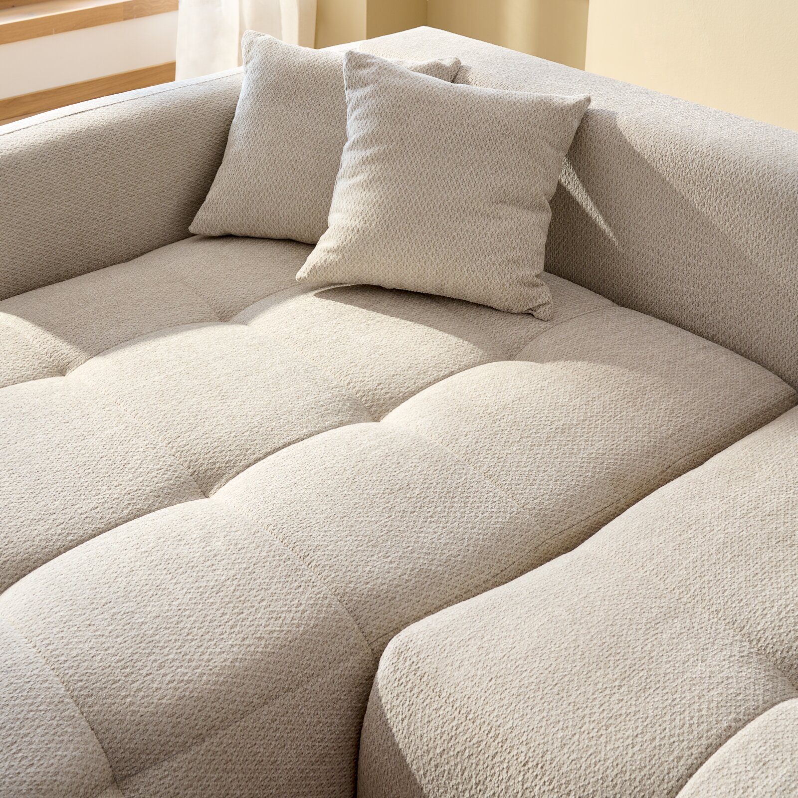 Nahaufnahme eines beigen Ecksofas mit Kissen, Perspektive von oben