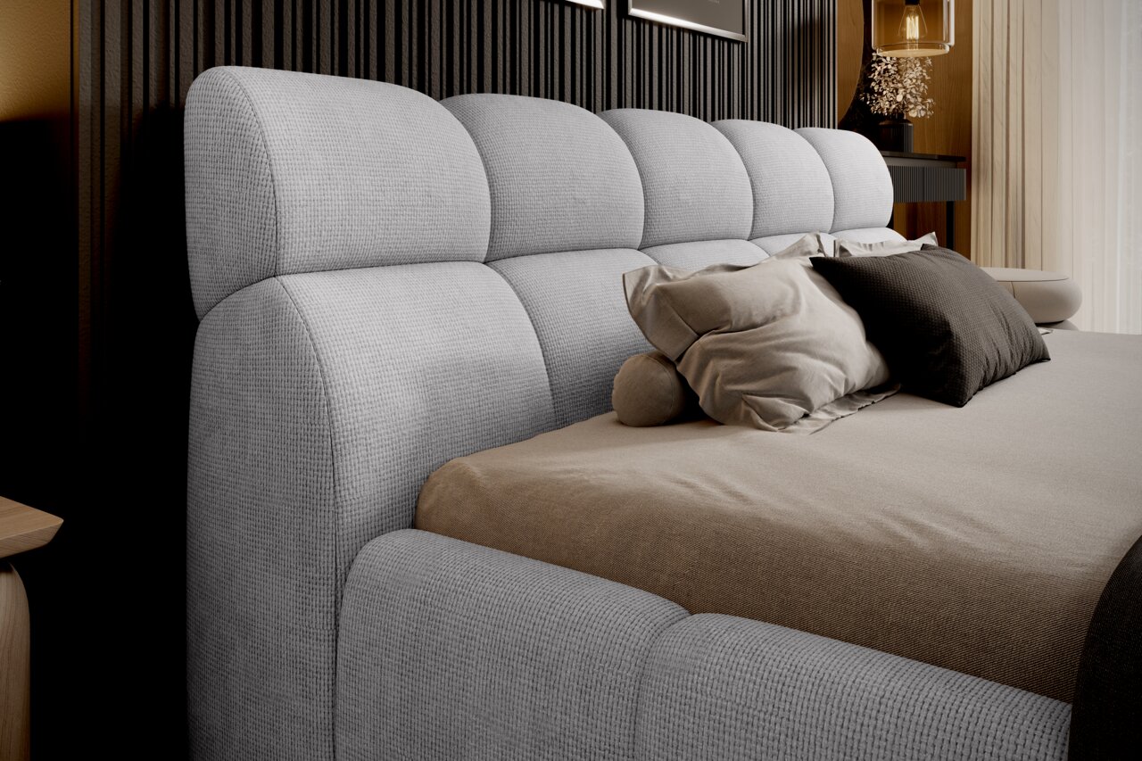 Seitliche Perspektive eines modernen Polsterbetts mit grauem Kopfteil und bequemen Kissen.