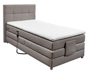 Boxspringbett in seitlicher Perspektive mit grauem Stoffbezug und weißem Topper, inklusive Fernbedienung.