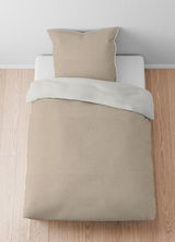 Bettwäsche-Set aus Melange-Flanell in Beige, bestehend aus einem Kissenbezug und einem Bettdeckenbezug, von oben fotografiert auf einem Holzboden.