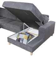 Graues Ecksofa mit hochgeklappter Sitzfläche, die Stauraum mit bunten Kissen zeigt, Perspektive von schräg oben.