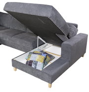 Graues Ecksofa mit hochgeklappter Sitzfläche, die Stauraum mit bunten Kissen zeigt, Perspektive von schräg oben.