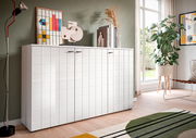 Modernes weißes Sideboard mit quadratischem Muster, dekoriert mit Kunstwerken und Büchern, in einem stilvoll eingerichteten Raum mit Pflanzen und großen Fenstern, seitliche Perspektive.