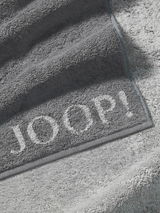 Graues Handtuch von JOOP! mit eingewebtem Logo, Nahaufnahme der Textur und Kanten.