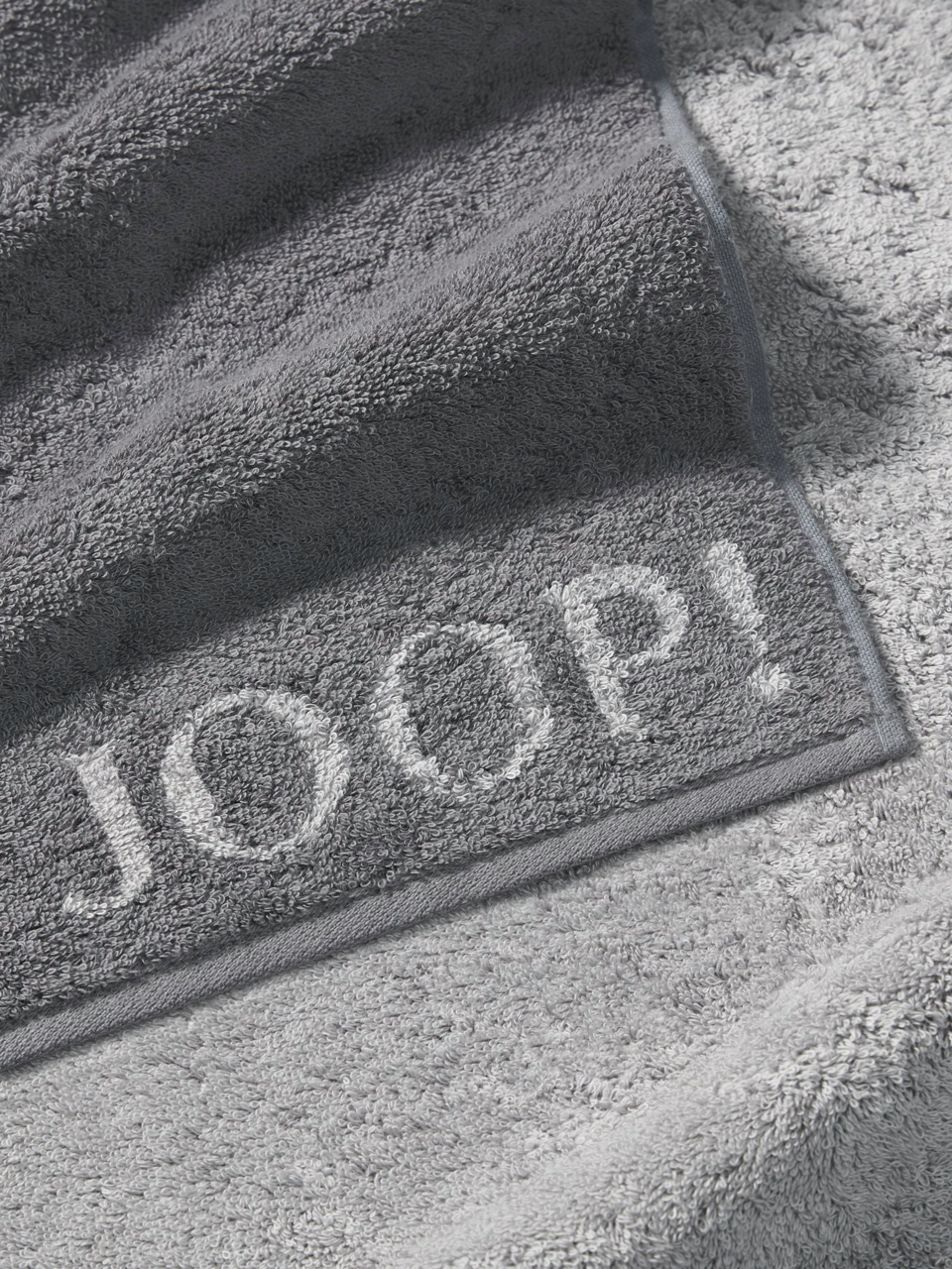 JOOP! Handtuch DOUBLEFACE CLASSIC Graues Handtuch von JOOP! mit eingewebtem Logo, Nahaufnahme der Textur und Kanten.