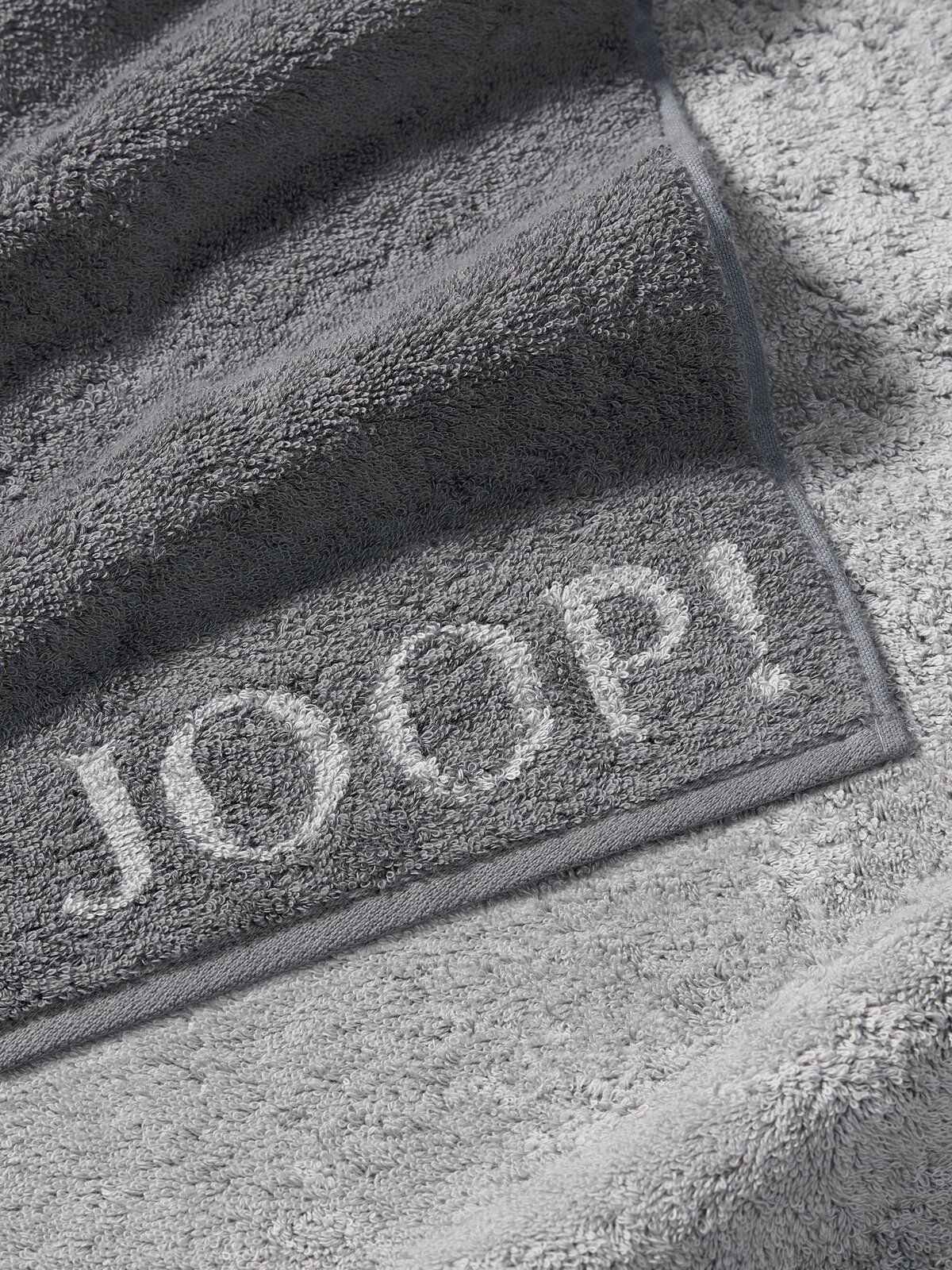 JOOP! Handtuch DOUBLEFACE CLASSIC Graues Handtuch von JOOP! mit eingewebtem Logo, Nahaufnahme der Textur und Kanten.