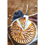 Kuchenheber aus Edelstahl, von oben fotografiert, neben einem Apfelkuchen auf einem Holztisch.