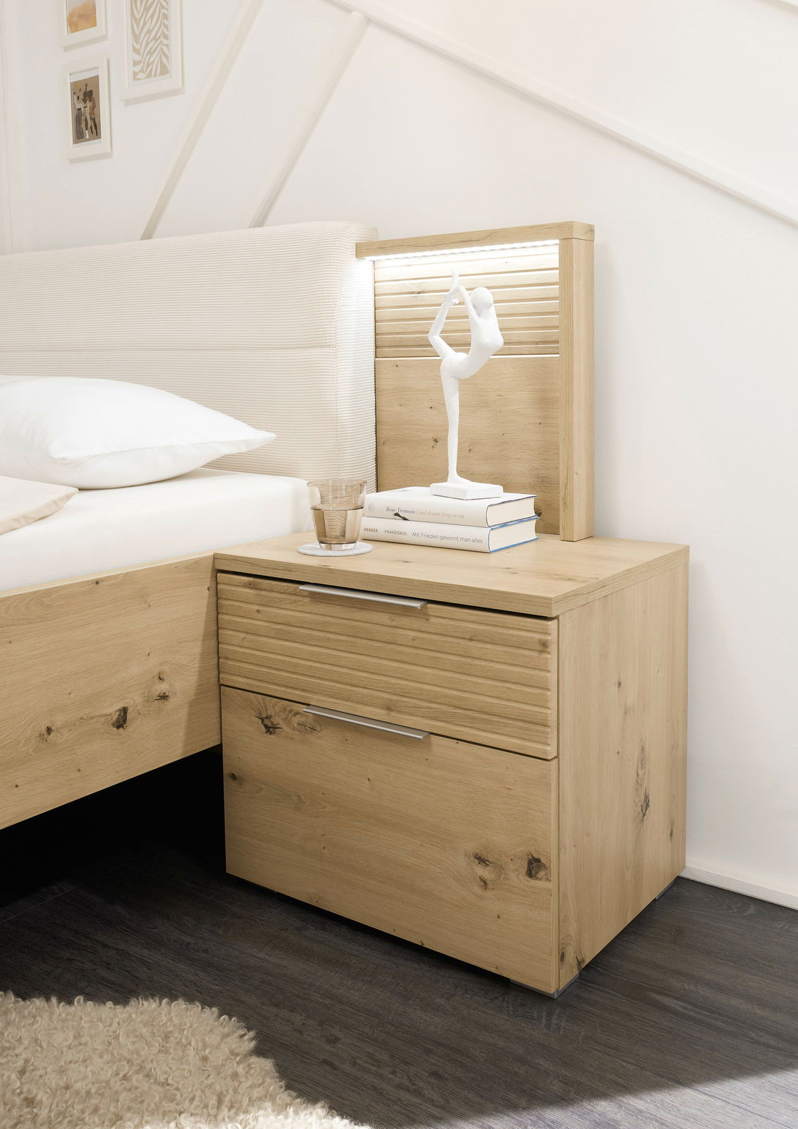 Nachttisch aus Holz mit zwei Schubladen, dekoriert mit einer weißen Skulptur und Büchern, seitliche Perspektive