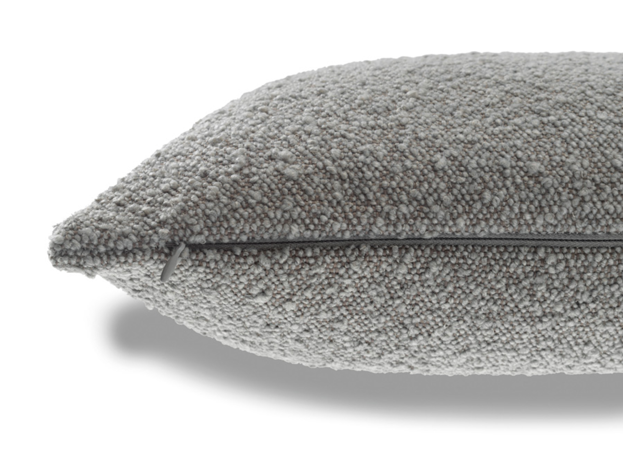 Graue Zierkissenhülle mit strukturierter Oberfläche, seitliche Perspektive mit sichtbarem Reißverschluss.
