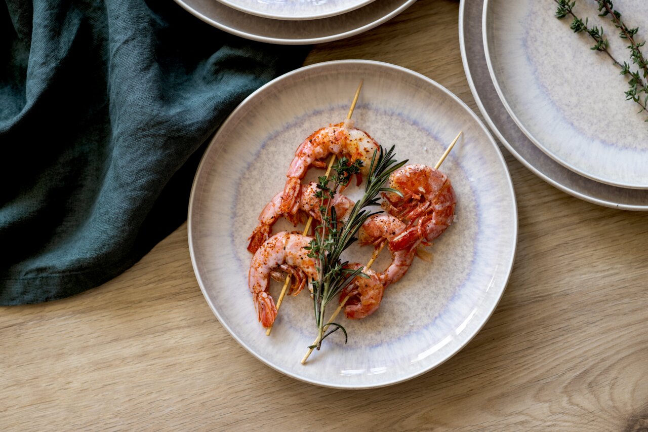 Speiseteller mit Garnelenspießen und Kräutern, von oben fotografiert