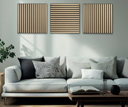 Drei Akustikpaneele in Holzoptik an der Wand über einem modernen Sofa, frontal betrachtet.