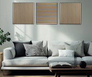 Drie akoestische panelen met houtlook aan de muur boven een moderne bank, gezien van voren.
