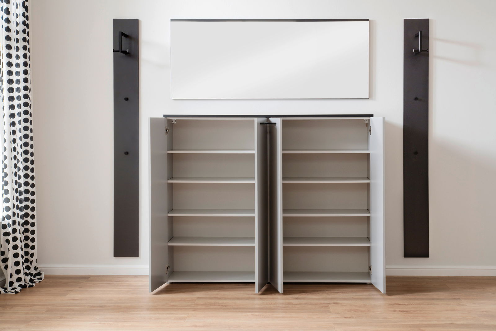 Moderano Vorschlagskombi Garderobe ALMADA Offene Garderobe mit zwei Schränken und mehreren Regalböden, frontal fotografiert. An der Wand darüber befindet sich ein rechteckiger Spiegel, flankiert von zwei dunklen Wandpaneelen mit Haken.