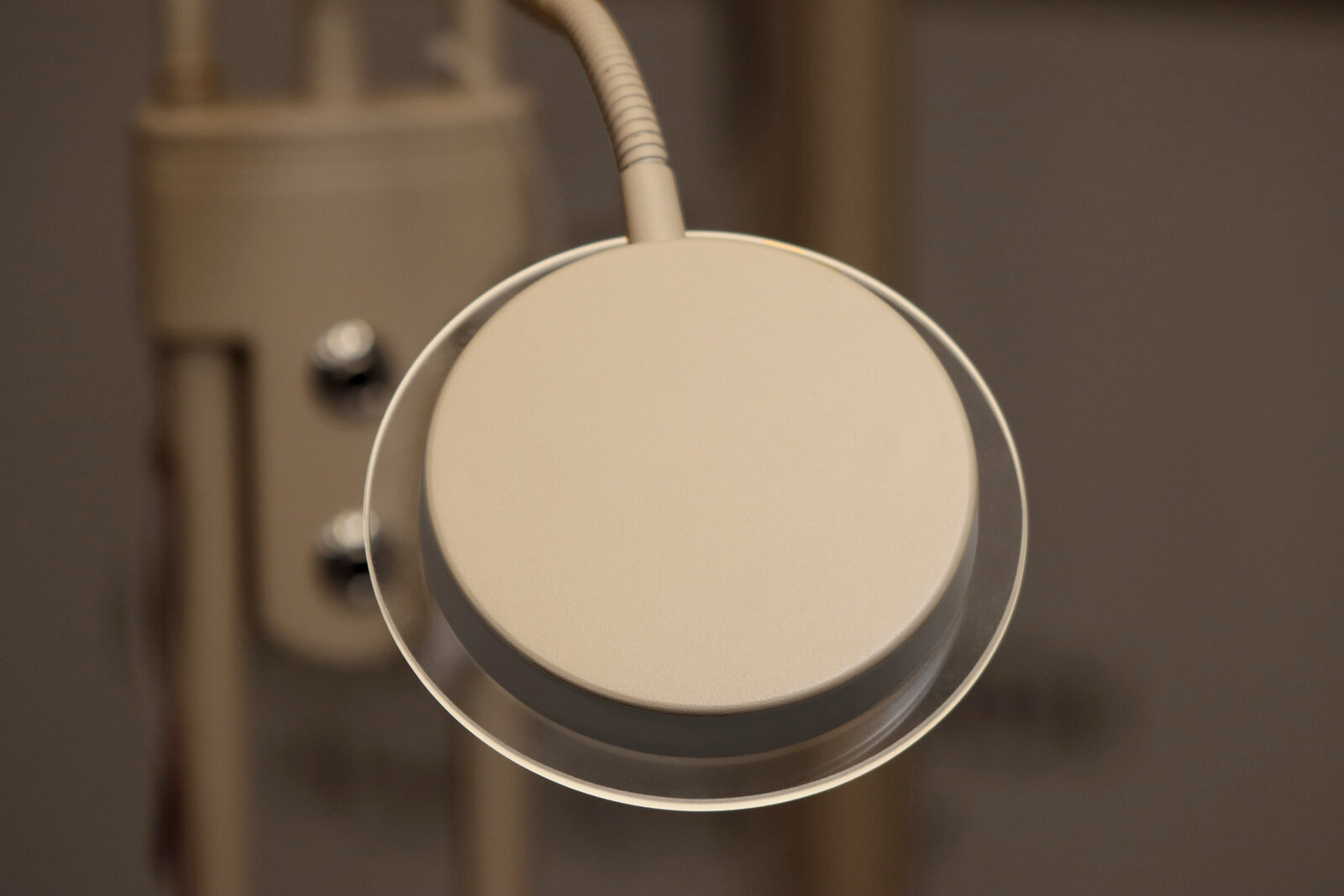 Runde, beige LED-Schreibtischlampe mit flexiblem Schwanenhals, Nahaufnahme von oben auf den Lampenkopf
