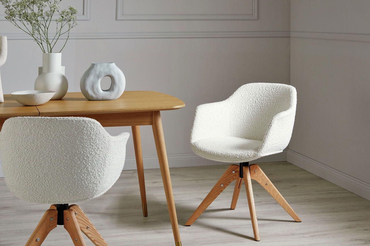 Zwei weiße Stühle mit Holzbeinen in einem modernen Esszimmer, einer von vorne und einer von hinten gesehen.