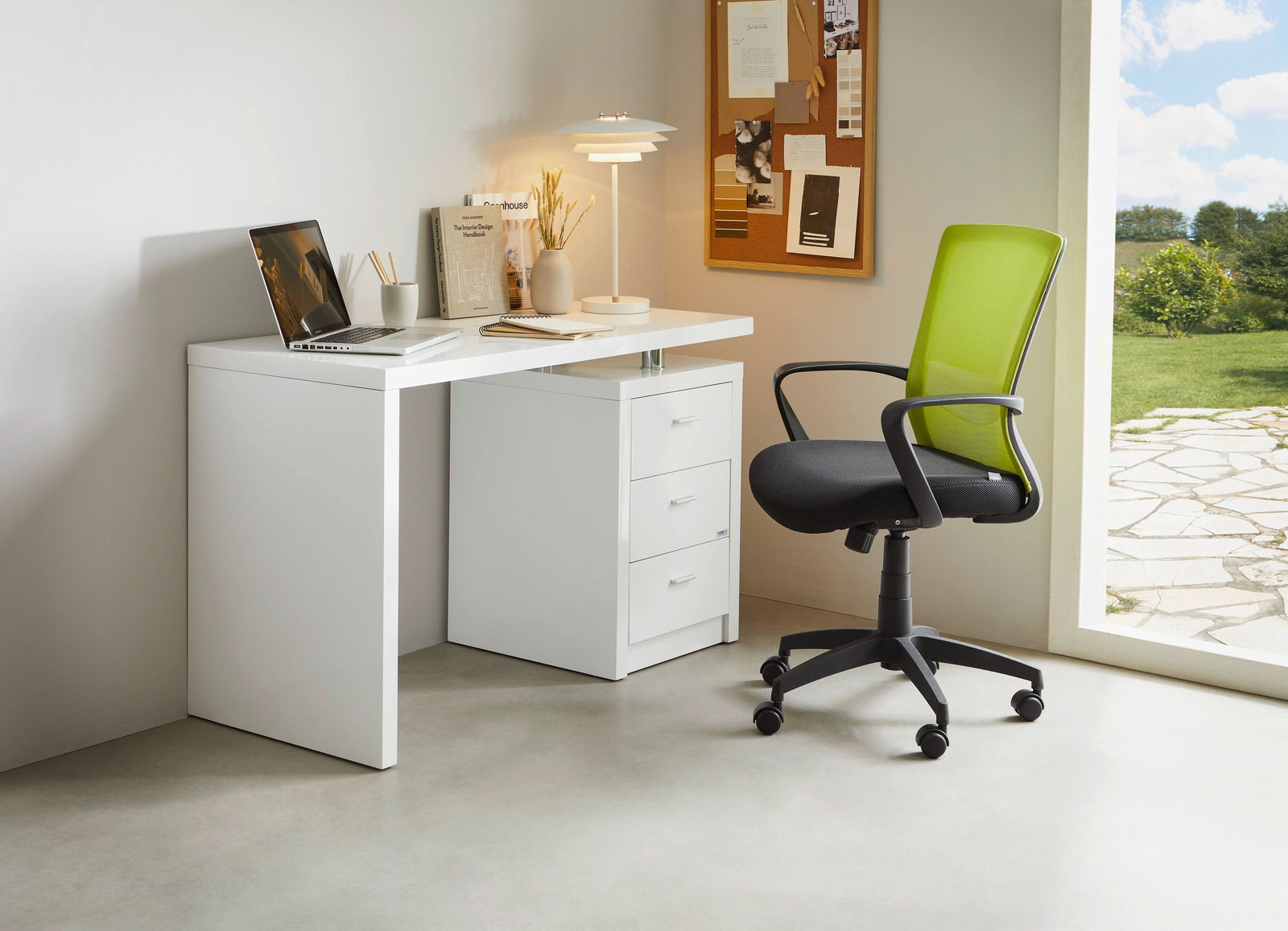 Carryhome Drehstuhl PAN Moderner Drehstuhl mit grünem Netzrücken und schwarzem Sitz, seitliche Perspektive, neben einem weißen Schreibtisch in einem hellen Raum.