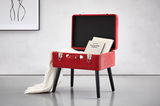 Roter Kofferhocker mit schwarzen Beinen, geöffnet, mit Büchern und einer weißen Decke, seitliche Perspektive