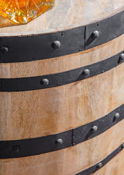 Nahaufnahme eines rustikalen Holzfasses mit schwarzen Metallbändern, von oben betrachtet.