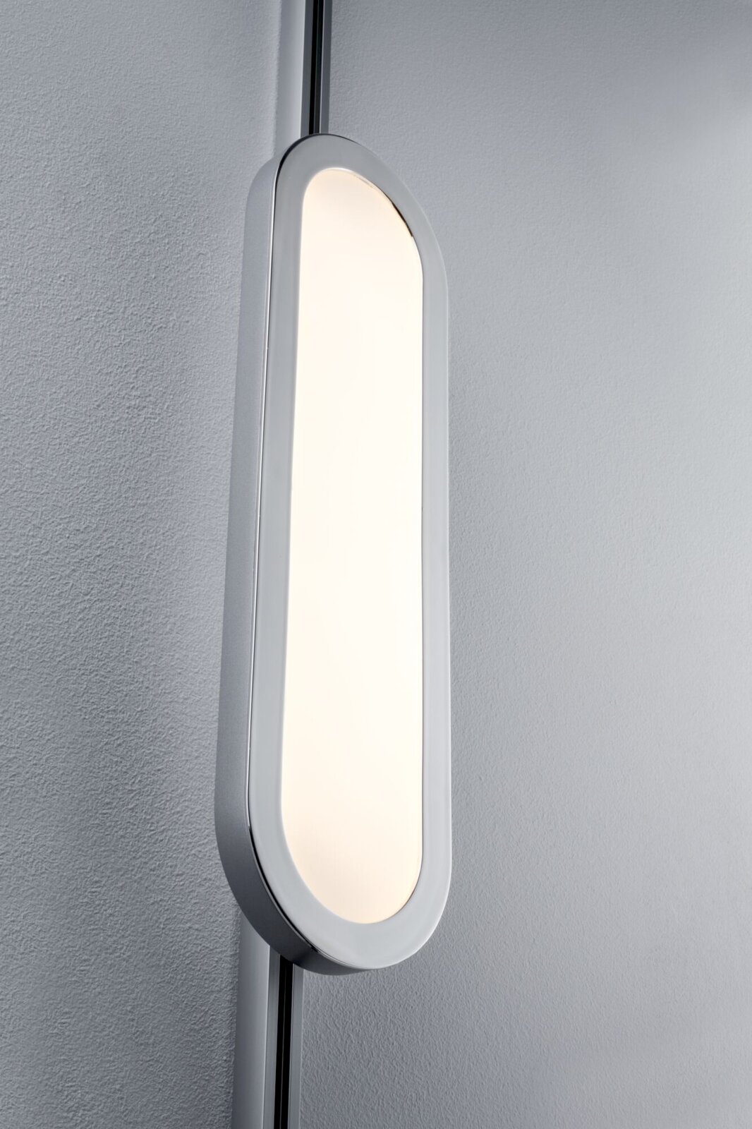 Nahaufnahme eines modernen, ovalen Schienenpanels mit sanftem Licht, montiert an einer Wand.