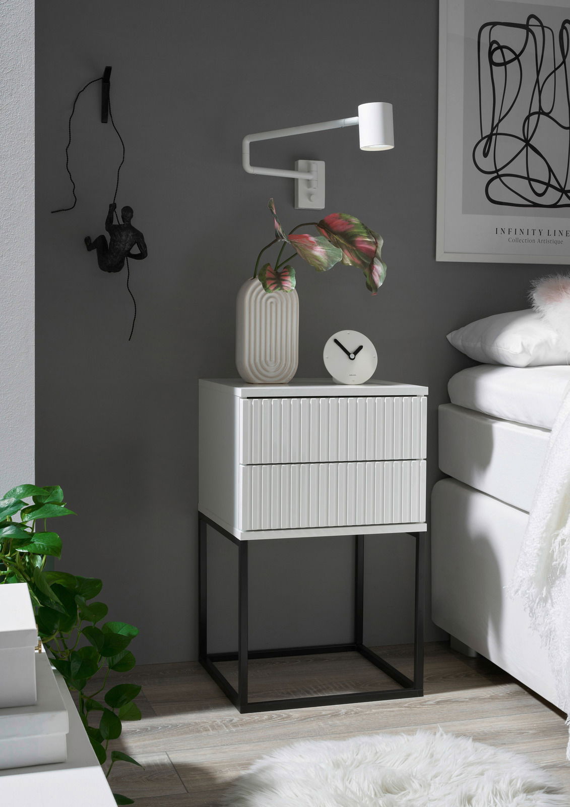 Moderne Nachtkommode mit zwei Schubladen, weiß mit geriffelter Front, auf schwarzem Metallgestell, seitliche Perspektive