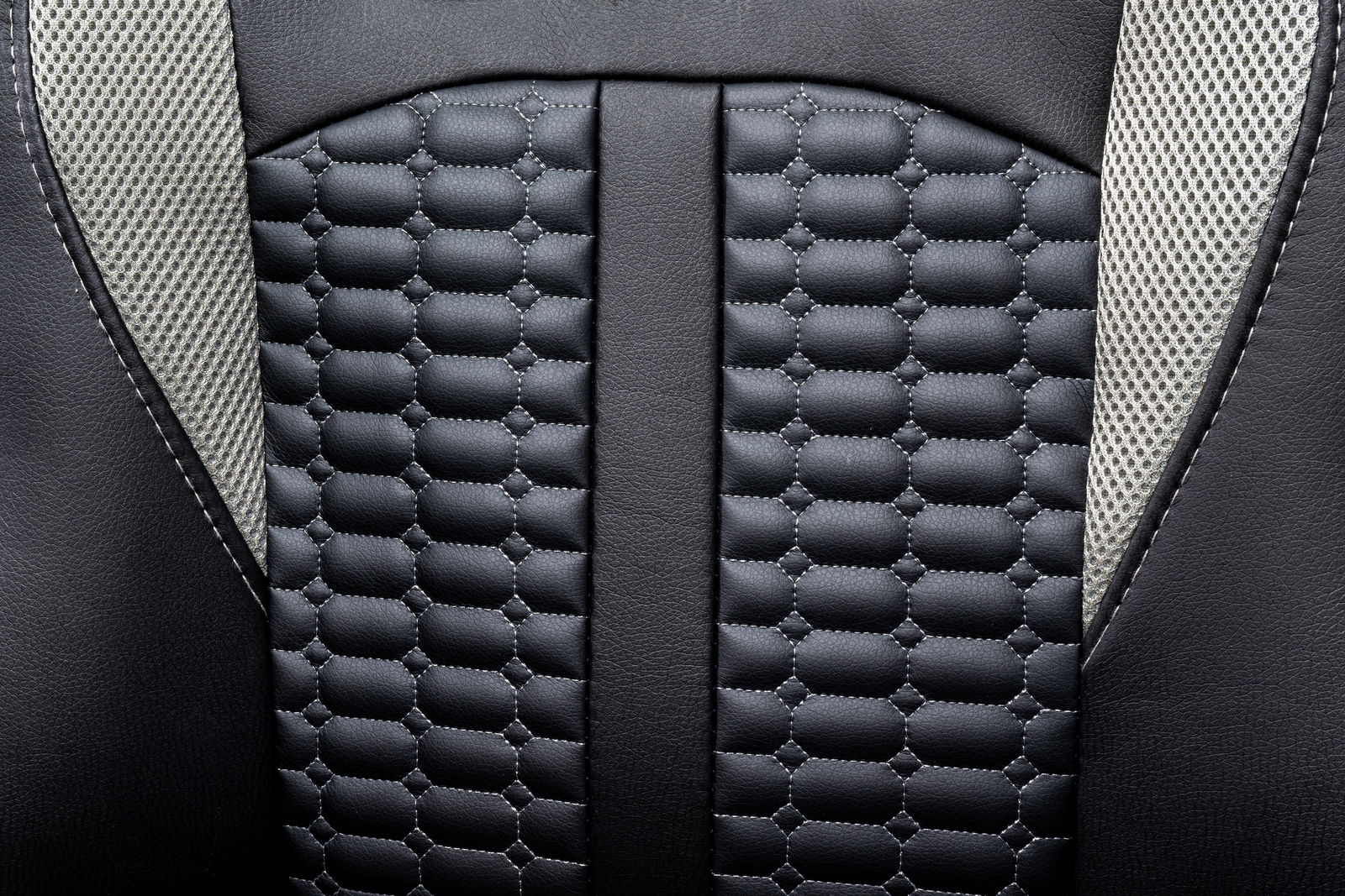 Nahaufnahme der Rückenlehne eines Gaming-Stuhls mit schwarzem, gepolstertem Leder und grauen Netzstoffakzenten.