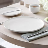 Eleganter Speiseteller Afina 27,2 cm in Seitenansicht auf gedecktem Tisch mit Besteck und Serviette.